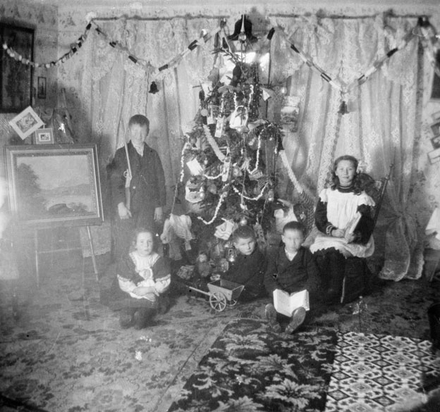Children with their toys around a decorated Christmas tree