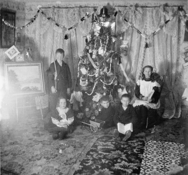 Children with their toys around a Christmas tree