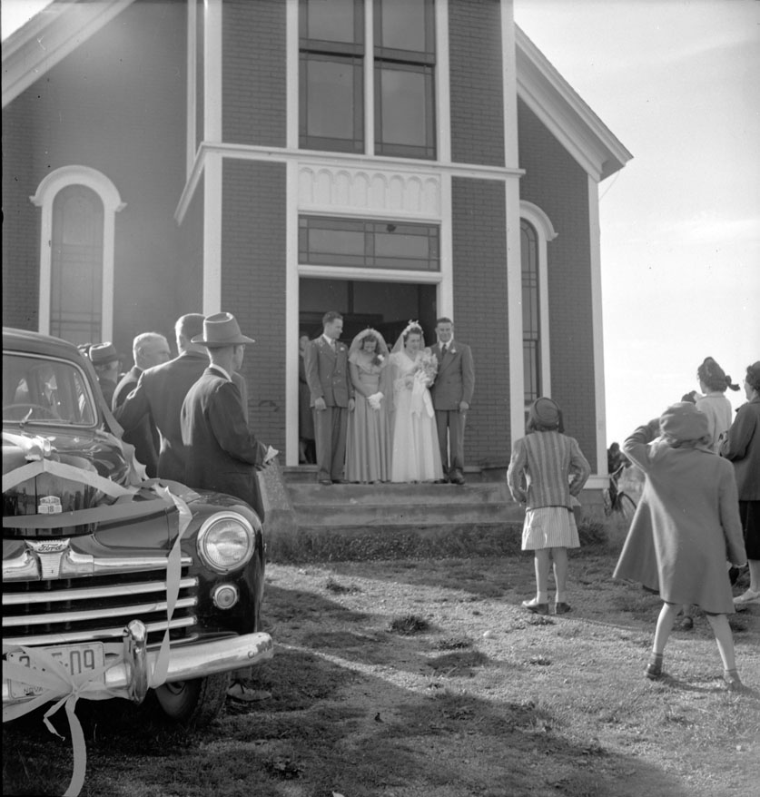 Wedding party in front of the church after the wedding of Evelyn-Theresa Thibodeau and Reed-Henry Melanson. Left to right: Herman Melanson, best man and brother of the groom; Rena Amirault, maid of honour and cousin of the bride; Evelyn-Theresa Thibodeau,