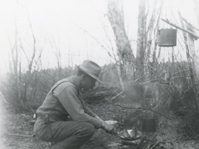 Man Cooking Fish Over a Campfire