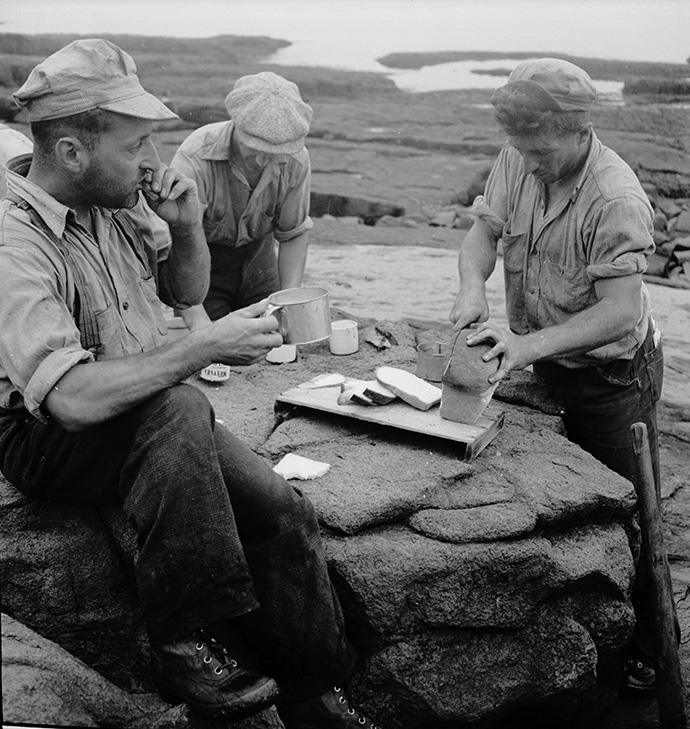 Logging crew eating their picnic lunch by the shore