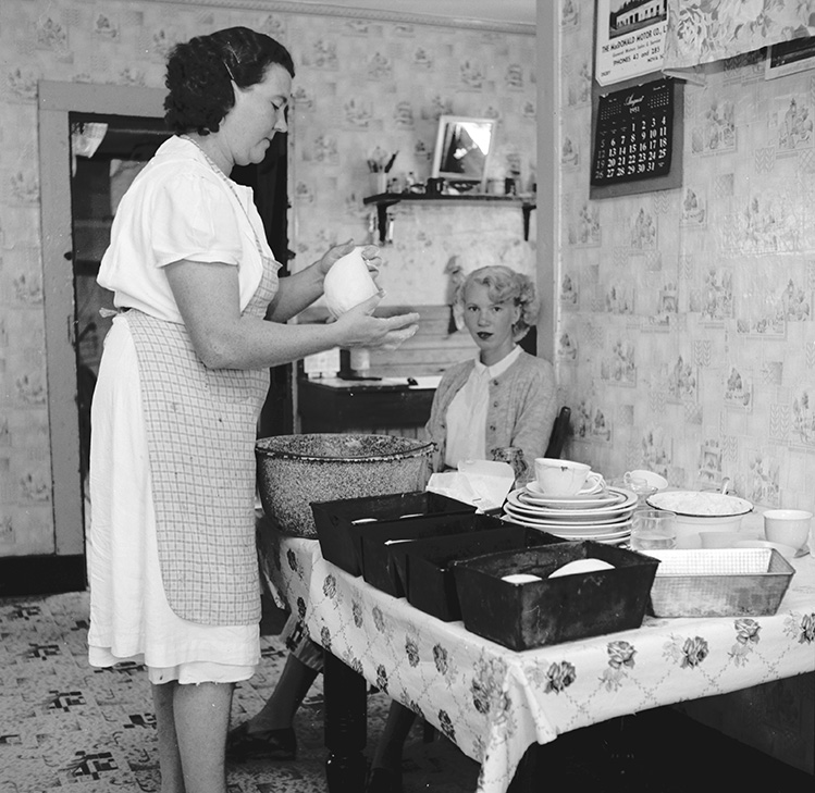 Mrs. Dugas making bread while her older daughter, Joyce, looks on