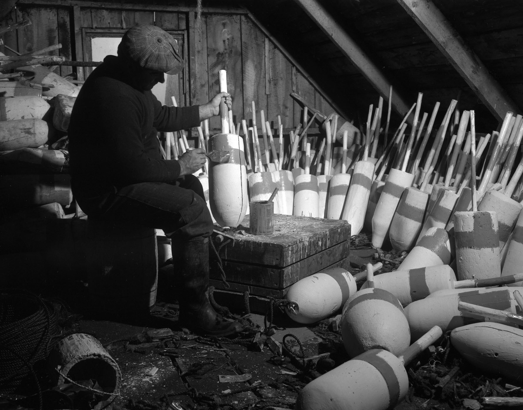 A fisherman paints buoys in his shed