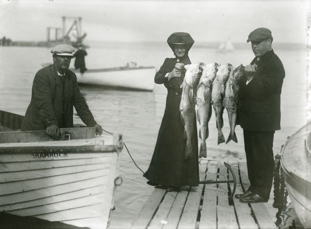 Man and Woman Showing Off Their Catch of Four Large Fish